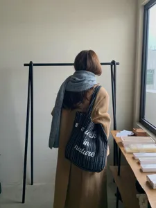 Vue de détail d'un sac cabas en toile rayé noir et blanc tendance pour l'hiver au quotidien.