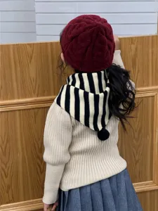 Vista muy detallada del pañuelo triangular a rayas para niños con un bonito pompón.