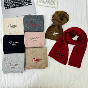 Detailansicht bunter Strickschals mit gesticktem Buchstaben-Design für Kinder.