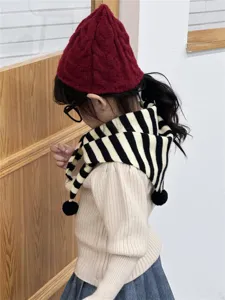 Detalle de bufanda triangular de punto a rayas cálida de invierno para niños con pompones.