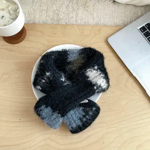 Nahaufnahme eines kuscheligen, farbblockierten Strickschals auf einer rustikalen Holztischplatte.