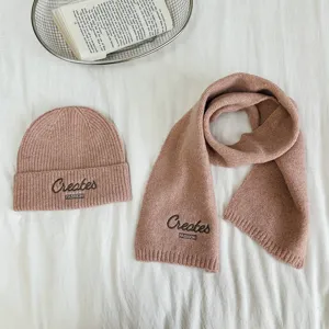 Nahaufnahme des rosa Strickmützen- und Schal-Sets für Kinder mit feinen Stickereien.