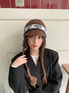 Brown Fair Isle knitted trapper hat with earflaps and braided tassel details for winter.