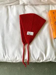 Rote gestrickte Winter-Ohrenschützer mit Bändern und Stoffetikett, kuschelig und stilvoll warm.