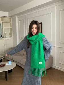 Cozy green wool blend winter scarf with playful tassels, stylish warm knit accessory for women.