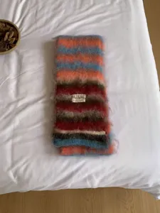 Detailansicht eines kuscheligen gestreiften Winterschals, weiche Plueschtextur mit bunten Streifen.