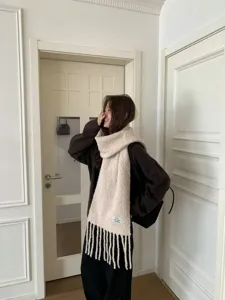 Detailed view of women's winter thick cozy beige fringe wool blend scarf, elegant warm accessory.