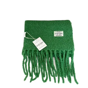 Green fuzzy winter scarf with long tassels and brand label, soft warm cozy fashion shawl.