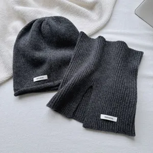 Detalle del conjunto de gorro y bufanda de lana gris oscuro, textura suave y etiqueta.