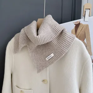 Detalle de bufanda de lana beige para mujer, suave punto acanalado para elegante estilo invernal.
