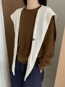 Detailed view of stylish wool button cross pointed shawl draped over brown knit sweater.