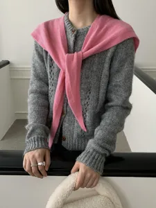 Close up detail of women grey knit cardigan paired with pink draped shoulder scarf outfit.