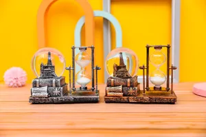 Detailed view of vintage Eiffel tower snow globe and hourglass desktop ornament for decor.
