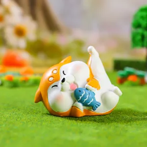 Gros plan sur la mignonne figurine shiba inu en résine tenant un poisson bleu pour auto.