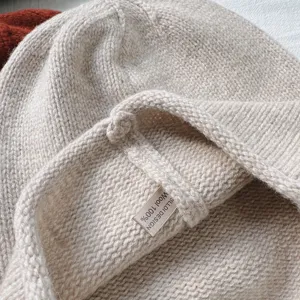 Primer plano de la tela del conjunto de gorro y bufanda de lana 100%, textura suave.