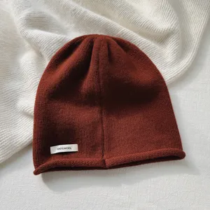 Primer plano de un acogedor gorro de pura lana marrón rojiza con textura de punto fina.