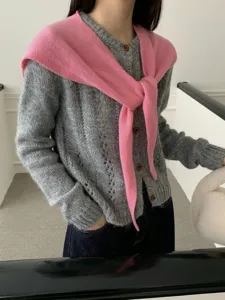 Close-up detail of the grey knit cardigan and pink draped shawl scarf, showing fine texture.