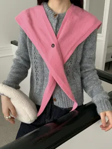 Detailed shot of the pink cross-shaped knitted shawl paired with grey wool cardigan.