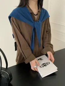 Detailed view of women's stylish wool knit shawl and long sleeve button-up shirt.