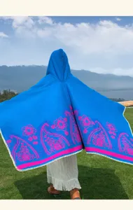 Detailed close-up of the blue hooded cape featuring vibrant pink paisley floral patterns.