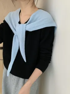 Close-up detail of the stylish light blue cross pointed knit shawl worn over black top.