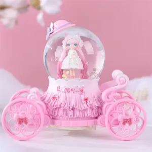 Gros plan détail de la boule à neige carrosse rose avec une jolie poupée et lumières.