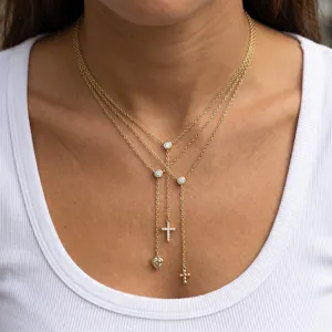 Collier multi-rangs doré en zircone avec pendentifs délicats de croix et de cœur.