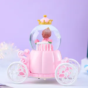 Detail van de roze koets sneeuwbol speeldoos met prinses en gouden kroon voor kinderen.