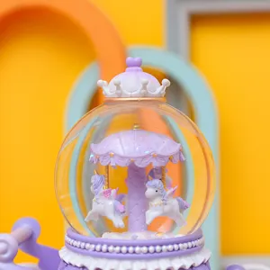Detailed view of a dreamy purple unicorn carousel snow globe music box gift ornament.