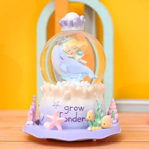 Detalle de caja de música bola de cristal temática oceánica, delfin y niña decor.