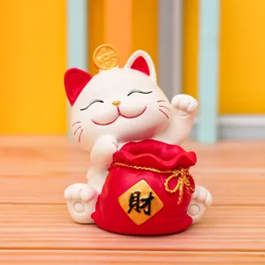 Dettaglio della statuetta del gatto portafortuna con sacchetto rosso, decorazione.