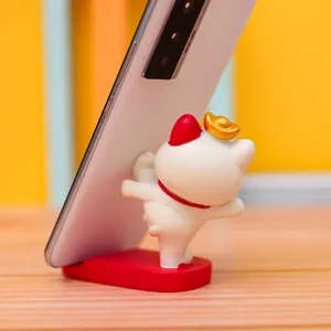 Close-up detail of the cute cat phone holder supporting a phone, showing stable red base.