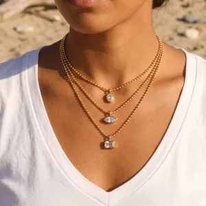 Close-up detail of multi-layer gold beaded chain necklace with geometric crystal pendants.