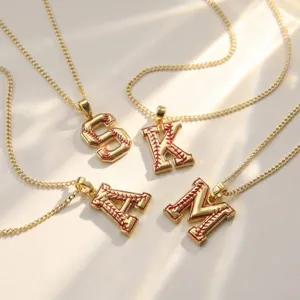 Vue rapprochée détaillée de colliers pendentifs lettre de baseball en laiton doré.