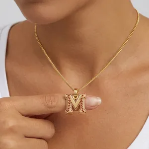 Vue de détail en gros plan du collier pendentif lettre M baseball avec coutures émail.