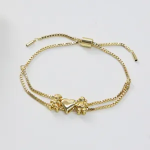 Bracelet coulissant double couche doré avec détail de pendentifs cœur et enfants.