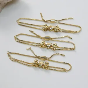 Bracelet de chaîne plaqué or avec pendentifs cœur et double figurine design réglable.
