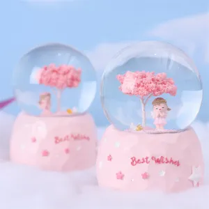 Detail view of the pink snow globe featuring a cherry blossom tree and angel figurine.