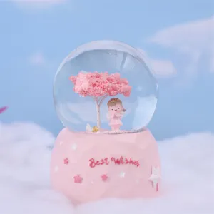 Pink snow globe detail shot, featuring cherry tree and cute angel figurine inside base.