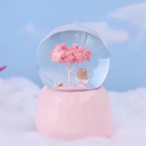 Pink snow globe with angel and cherry tree inside, perfect Valentine's day gift for home decor.