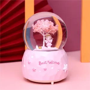 Detail view of the pink crystal snow globe featuring a cute praying angel and cherry tree.