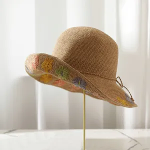 Detailansicht des handgefertigten Strohhutes mit bunter Blumenbestickung an der Krempe.