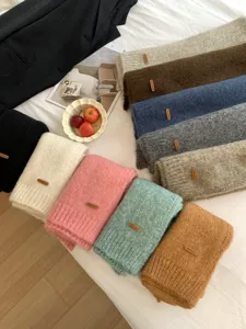 Detaillierte Flachbildaufnahme weicher Alpaka-Mischgewebe Einfarbiger Strickschals mit Lederaufnäher.
