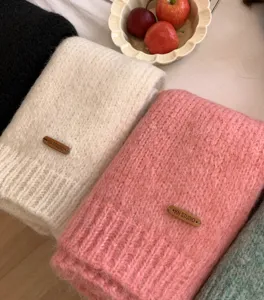 Nahaufnahme von weichem, kuscheligem Strickschal Detail mit Lederetikett für den Winter.