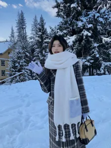 Detailaufnahme des warmen, dicken Kaschmir-Taschenschals mit Quasten im Winterschnee.
