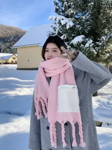 Detailansicht des rosa Strickschals mit weißer flauschiger Tasche und kuscheligen Fransen.
