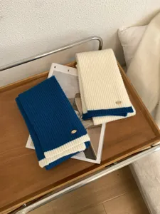 Detailansicht des farbblockierten Winter-Strickschals mit Metallschild, weicher Halswärmer.