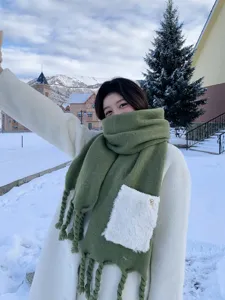 Gemütlicher grüner Winterschal mit flauschiger weißer Tasche und Quasten im Freien.