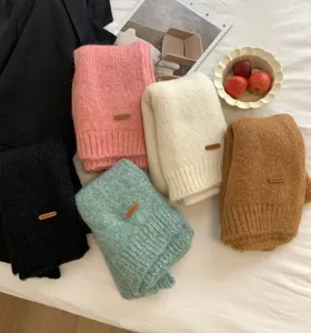Detailaufnahme von kuschelweichen, bunten Strickschals mit kleinem Lederetikett im Set.