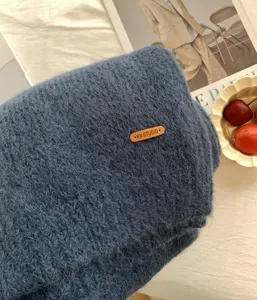 Kuschelweicher, blauer Strickschal im Detail mit dekorativem Lederetikett für den Winter.